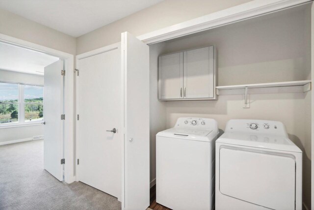 laundry area with light carpet, washing machine and clothes dryer, and cabinets