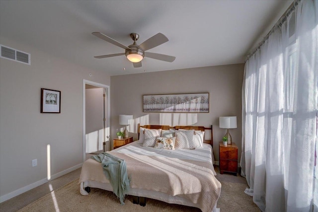 bedroom with visible vents, baseboards, a ceiling fan, and light carpet