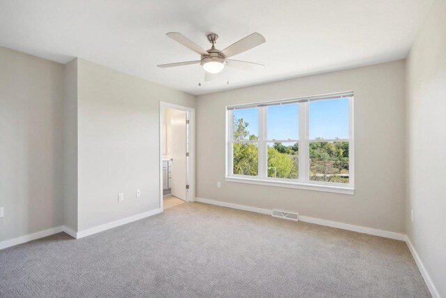 carpeted spare room featuring ceiling fan and a wealth of natural light