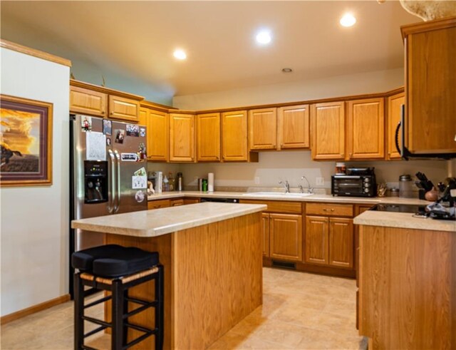 kitchen with a kitchen breakfast bar, light tile patterned flooring, sink, stainless steel appliances, and a center island