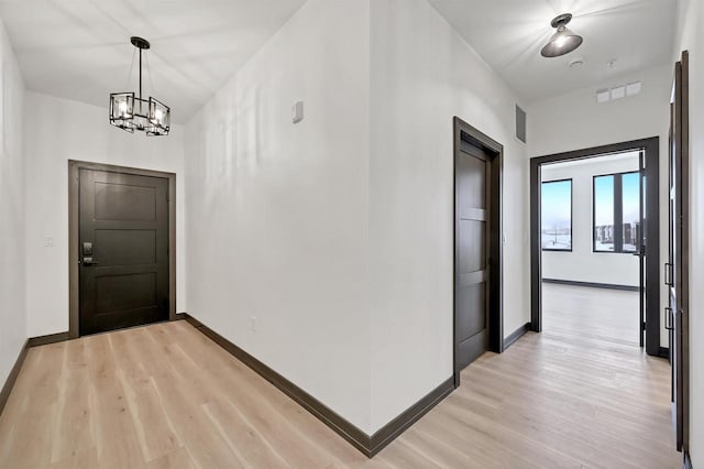 hallway featuring light wood finished floors, visible vents, and baseboards