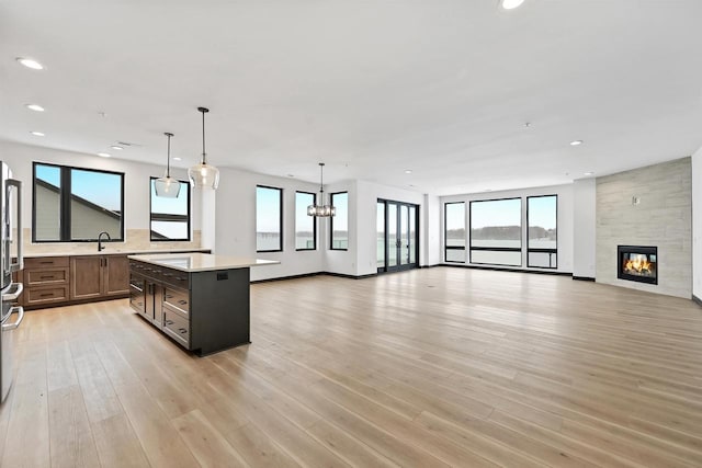 kitchen featuring light countertops, light wood-style flooring, open floor plan, a kitchen island, and a sink