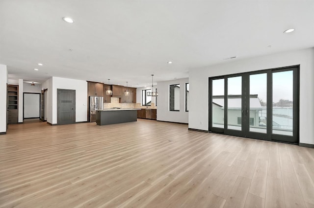 unfurnished living room with light wood-style floors, recessed lighting, and baseboards