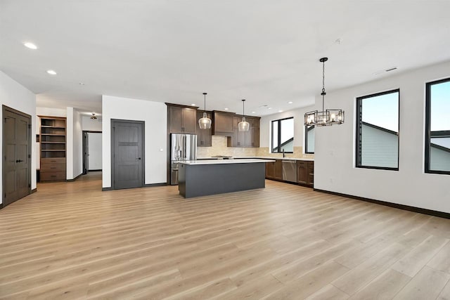 kitchen with a kitchen island, appliances with stainless steel finishes, light countertops, and dark brown cabinets