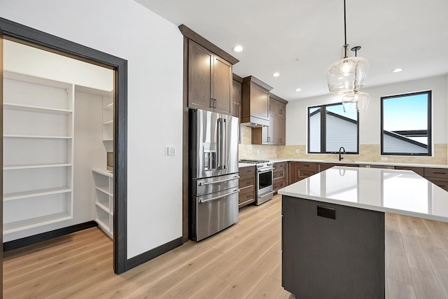 kitchen with light wood-style floors, stainless steel appliances, a sink, and light countertops