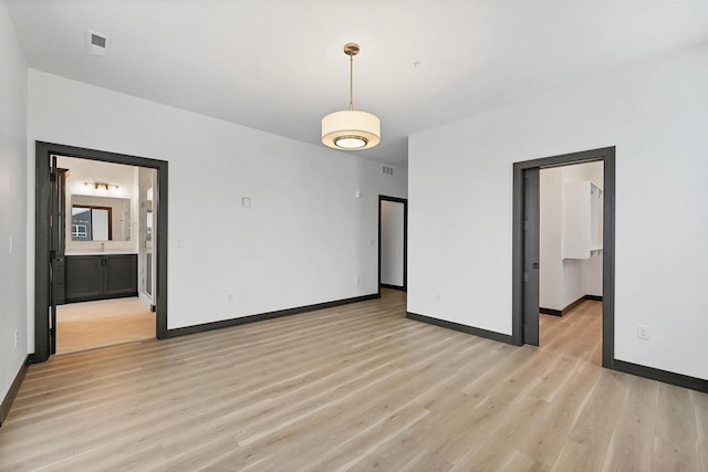 spare room featuring light wood-type flooring, baseboards, and visible vents