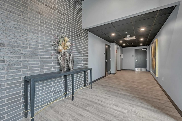 corridor with a paneled ceiling and light hardwood / wood-style flooring