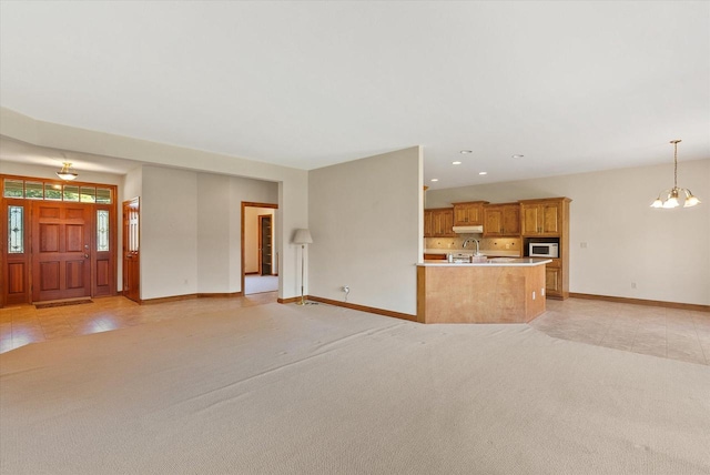 unfurnished living room featuring light colored carpet and a notable chandelier