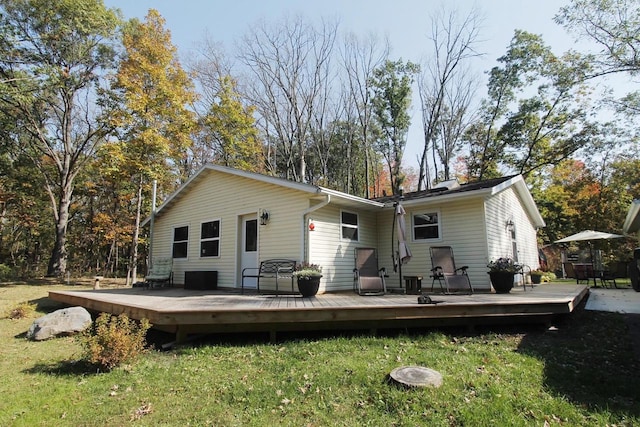 rear view of property with a wooden deck and a lawn