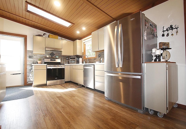 kitchen featuring vaulted ceiling with skylight, wooden ceiling, appliances with stainless steel finishes, and light wood-type flooring