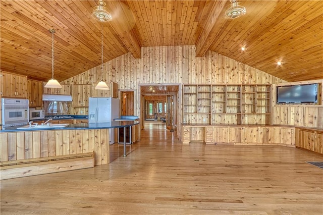 6874N Victory Heights Cir, Stone Lake, WI 54876 - kitchen featuring wooden walls, white appliances, dark countertops, under cabinet range hood, and light wood-style floors