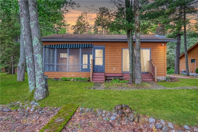 6874N Victory Heights Cir, Stone Lake, WI 54876 - view of front facade with entry steps, a yard, a chimney, and a sunroom