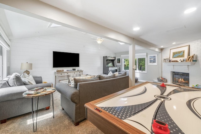 living room featuring ceiling fan, a fireplace, light carpet, and vaulted ceiling