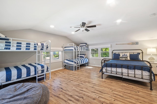 bedroom with vaulted ceiling, hardwood / wood-style flooring, multiple windows, and ceiling fan