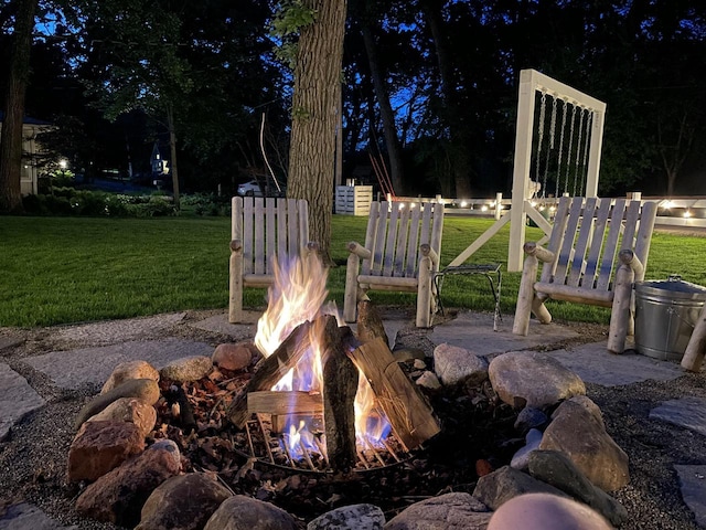 patio at night featuring a fire pit and a yard