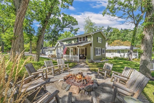 back of house featuring a yard, a patio area, and an outdoor fire pit