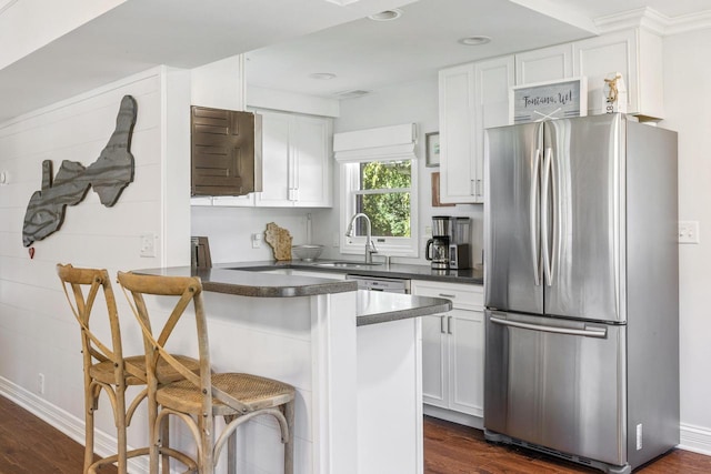 kitchen featuring stainless steel fridge, a kitchen breakfast bar, sink, kitchen peninsula, and white cabinets