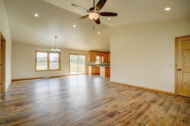 unfurnished living room with light hardwood / wood-style floors, high vaulted ceiling, and ceiling fan with notable chandelier