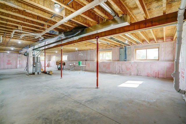 basement featuring electric panel and heating unit