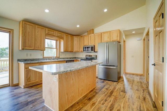 kitchen featuring sink, a kitchen island, appliances with stainless steel finishes, light brown cabinetry, and light hardwood / wood-style floors