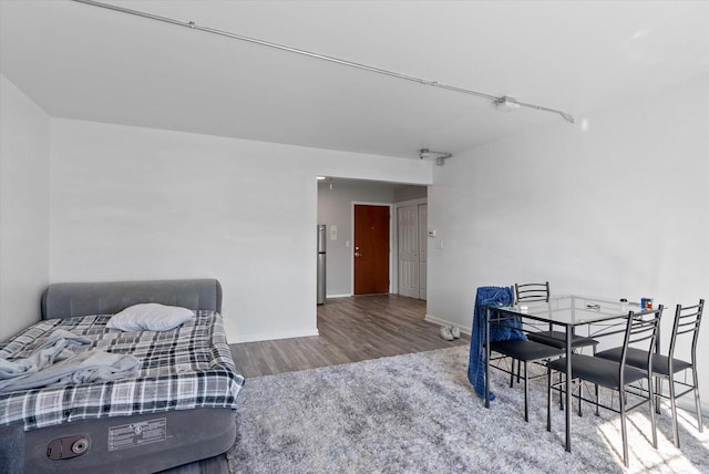 bedroom with stainless steel fridge and hardwood / wood-style floors