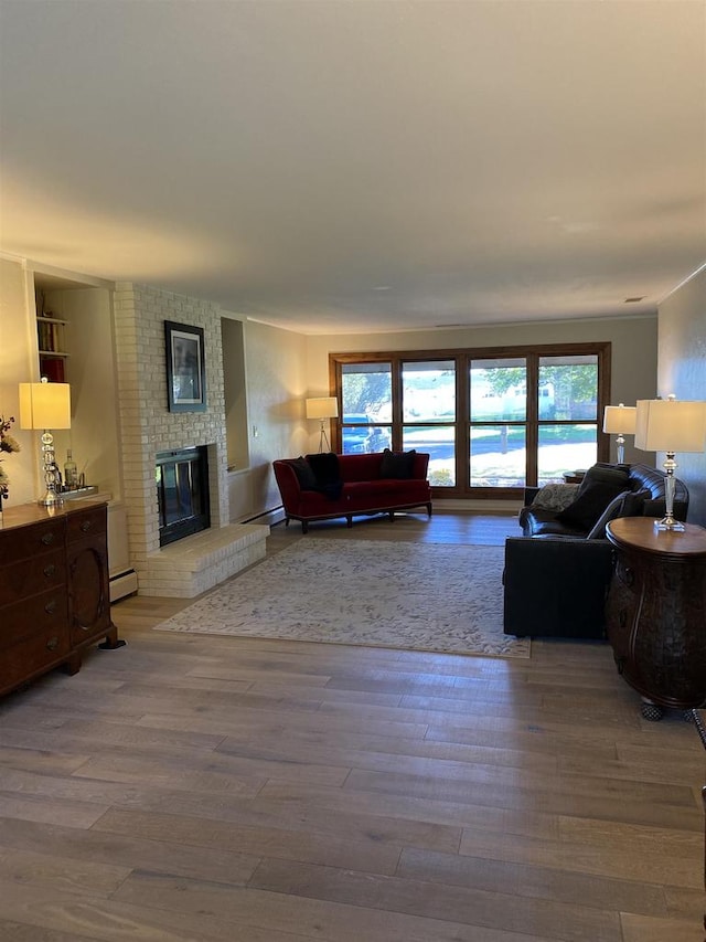 living room featuring a fireplace, light hardwood / wood-style floors, and baseboard heating