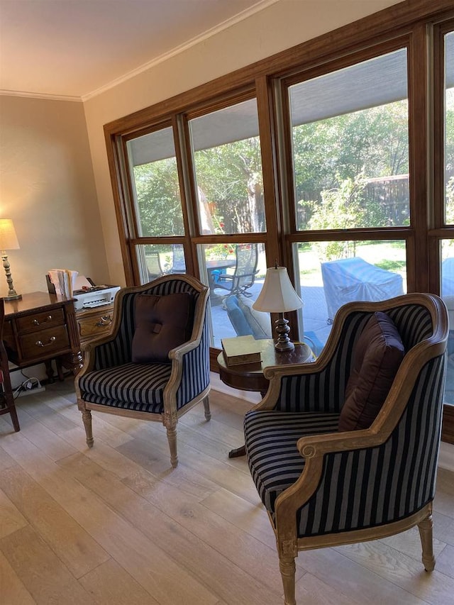 sitting room with ornamental molding and light hardwood / wood-style flooring