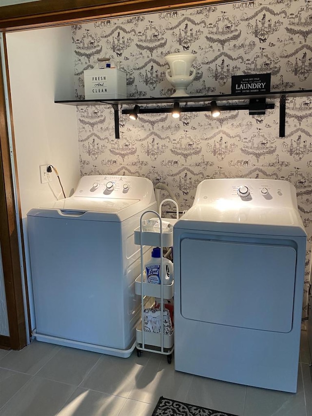 clothes washing area with washer and clothes dryer and dark tile patterned floors