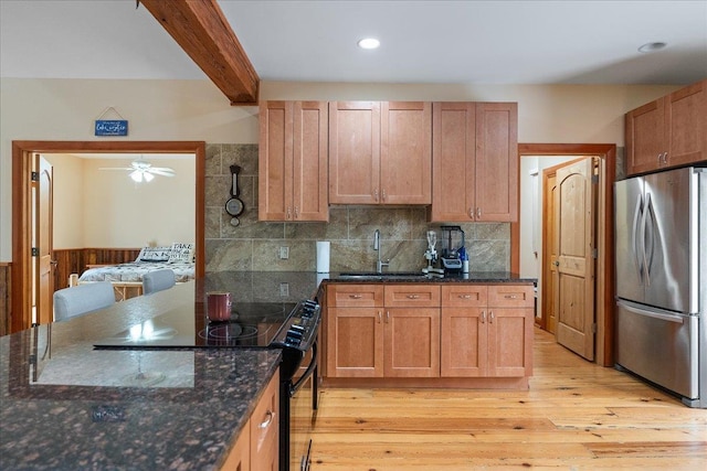 kitchen featuring stainless steel refrigerator, black range, light wood-type flooring, ceiling fan, and sink