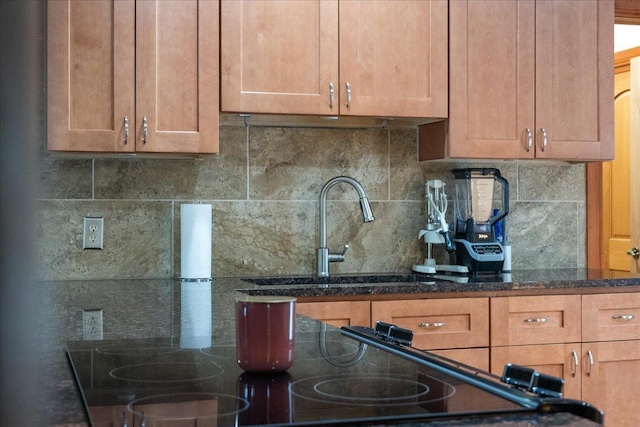 kitchen with dark stone counters, sink, and decorative backsplash