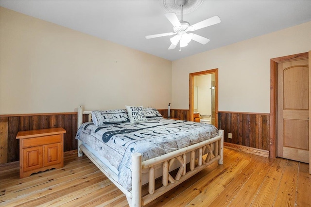 bedroom featuring wooden walls, ceiling fan, and light hardwood / wood-style floors