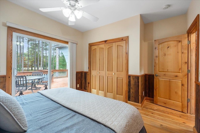 bedroom with access to outside, hardwood / wood-style flooring, wooden walls, and ceiling fan