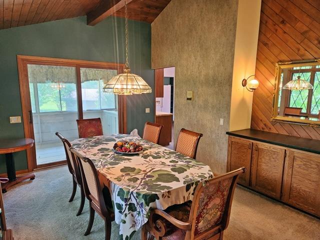 carpeted dining space featuring high vaulted ceiling, beamed ceiling, a wealth of natural light, and wooden ceiling