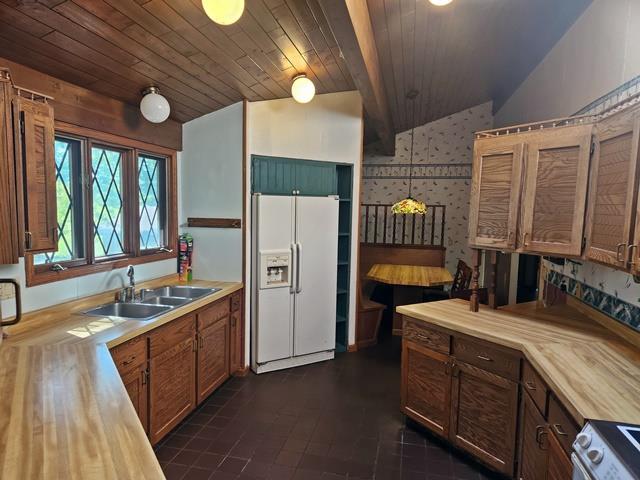 kitchen with lofted ceiling, sink, white appliances, decorative light fixtures, and wooden ceiling