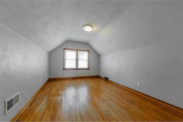 additional living space featuring light wood-type flooring and vaulted ceiling