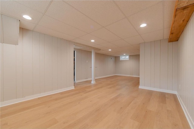 basement with a paneled ceiling and light hardwood / wood-style floors