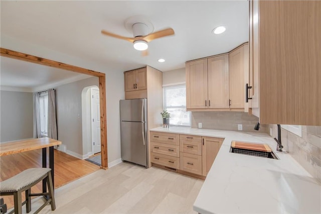 kitchen featuring stainless steel fridge, backsplash, light hardwood / wood-style floors, and light brown cabinetry