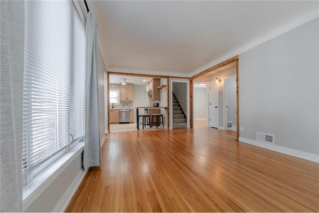 unfurnished living room featuring ceiling fan, sink, and light wood-type flooring