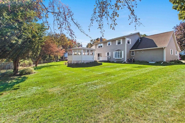 rear view of house with a sunroom, central air condition unit, and a lawn