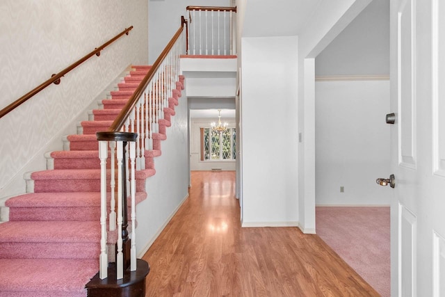 stairway featuring hardwood / wood-style floors and a notable chandelier