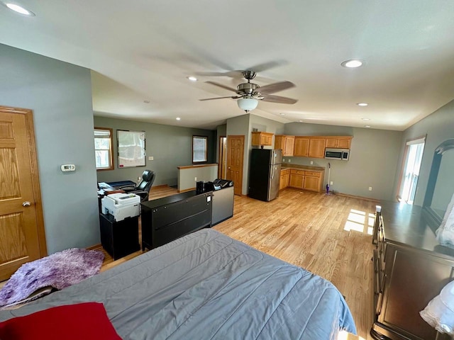 bedroom with lofted ceiling, stainless steel fridge, multiple windows, and ceiling fan