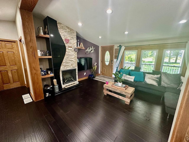 living room featuring a stone fireplace, wood-type flooring, and vaulted ceiling