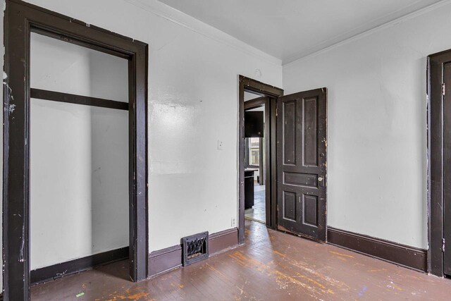 unfurnished bedroom featuring ornamental molding and dark hardwood / wood-style flooring