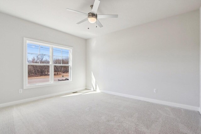 carpeted empty room featuring ceiling fan and baseboards