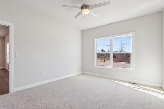 carpeted empty room with a ceiling fan and baseboards