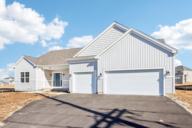 view of front facade with a garage, driveway, a shingled roof, and board and batten siding