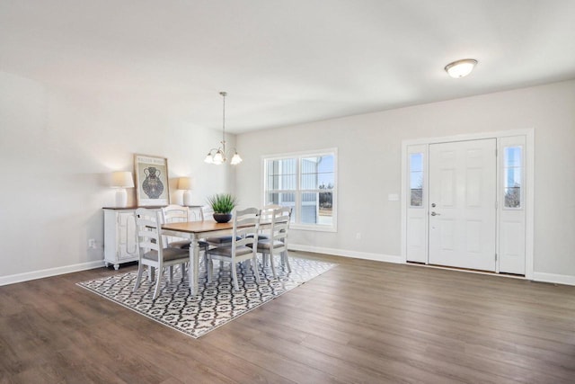 dining space with a notable chandelier, baseboards, and wood finished floors