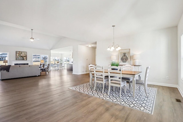 dining room featuring lofted ceiling, visible vents, baseboards, and wood finished floors