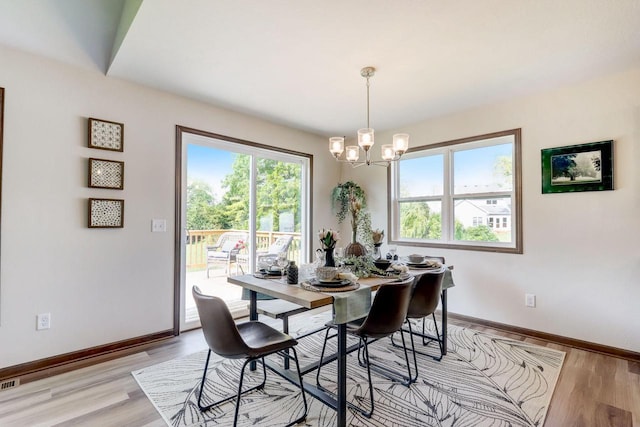 dining space featuring light hardwood / wood-style floors and an inviting chandelier