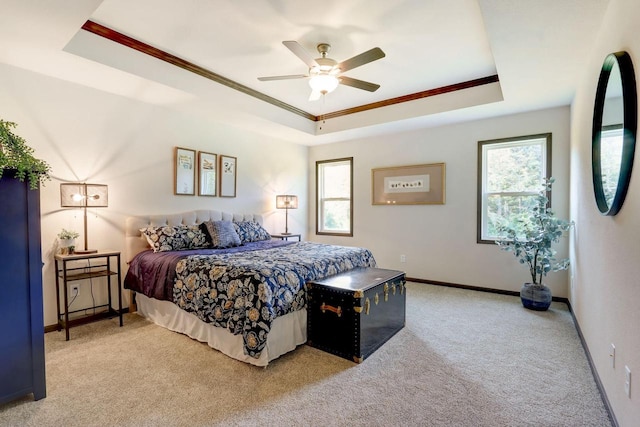 carpeted bedroom with multiple windows, ceiling fan, a tray ceiling, and crown molding